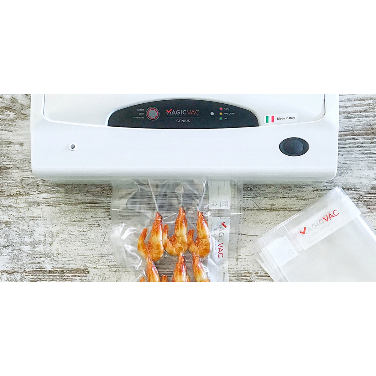 Biała zgrzewarka Magic Vac zgrzewająca torebkę z krewetkami na drewnianej powierzchni.