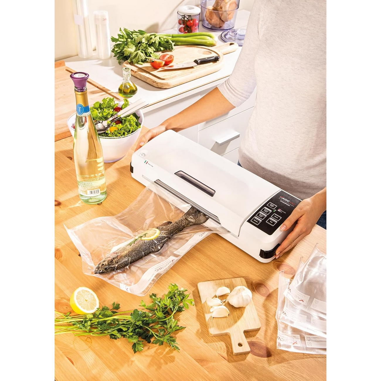 Kobieta zamykająca rybę w worku za pomocą zgrzewarki próżniowej. Inne przedmioty na blacie.