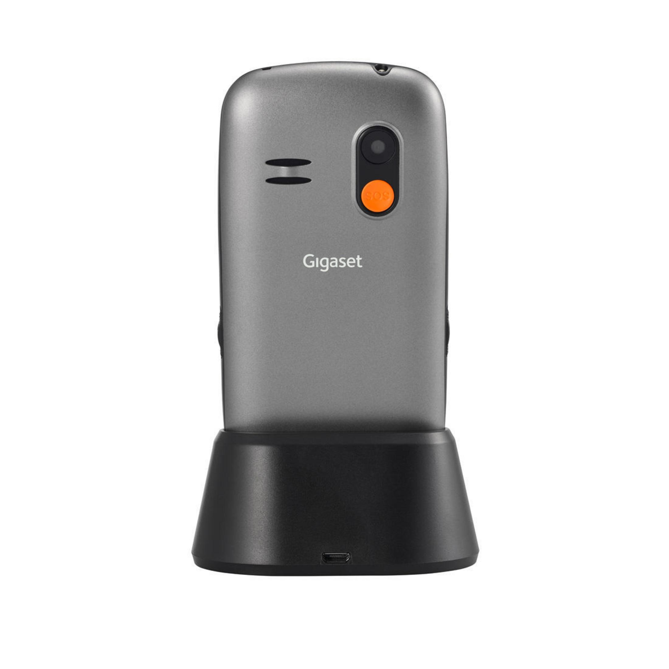 Telefono cordless grigio su un caricatore. Il telefono ha pulsanti e un piccolo schermo.