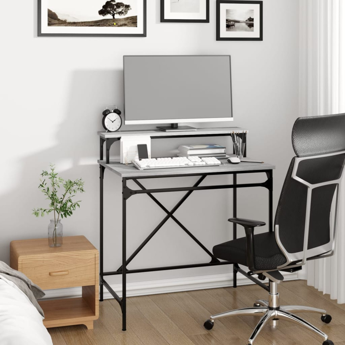 Ein Schreibtisch mit Monitor, Tastatur und Stuhl. Eine Pflanze und ein Nachttisch sind links.