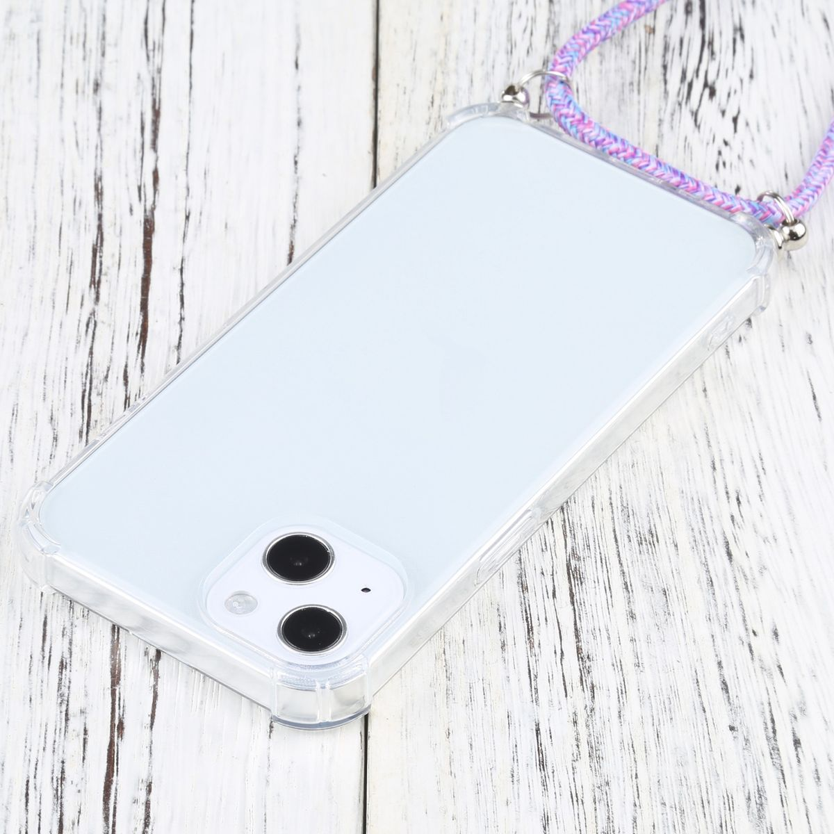 Transparente Handyhülle mit lila Kordel. Das Handy liegt auf einer weißen Holzoberfläche.