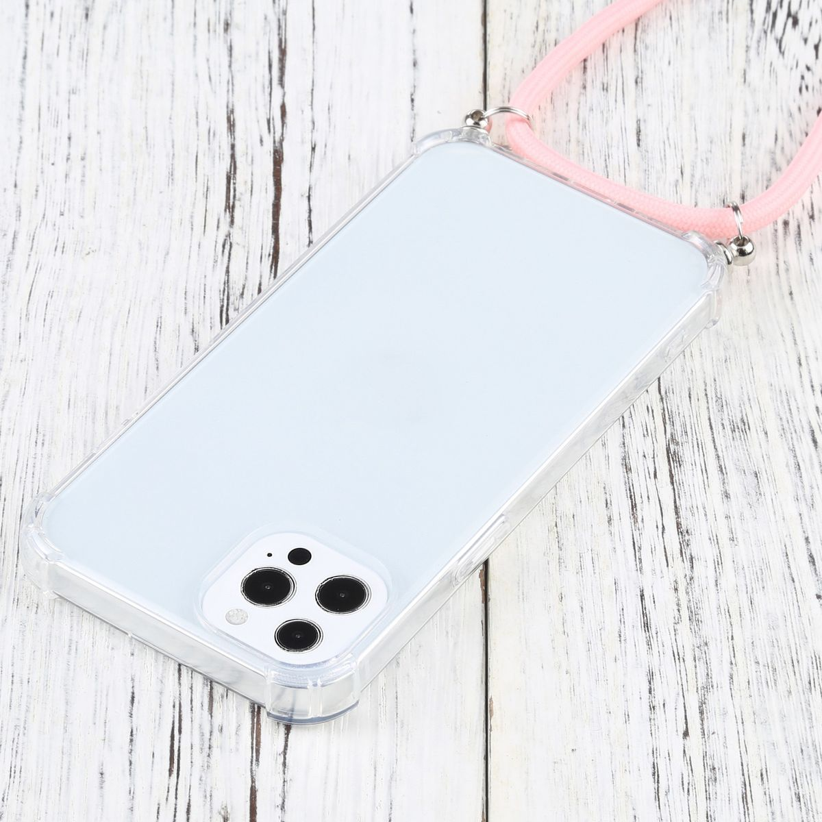 Eine transparente Handyhülle mit einem rosa Schlüsselband. Das Telefon liegt auf einer weißen Holzoberfläche.