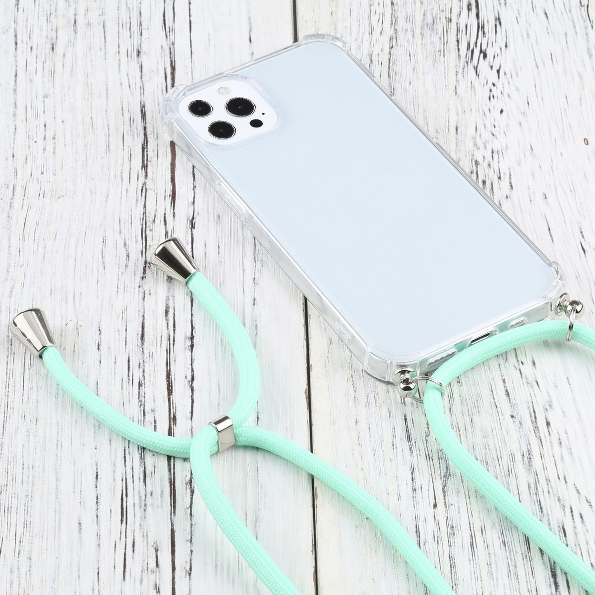 Eine transparente Handyhülle mit einem hellgrünen Umhängeband. Das Telefon liegt auf Holz.