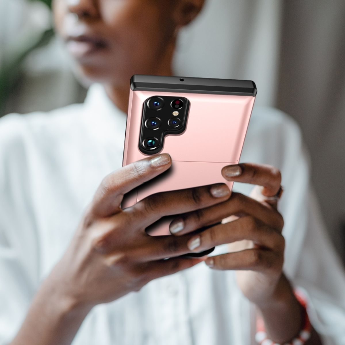 Frau hält eine rosa Handyhülle. Telefon hat mehrere Kameras und einen schwarzen Rahmen.