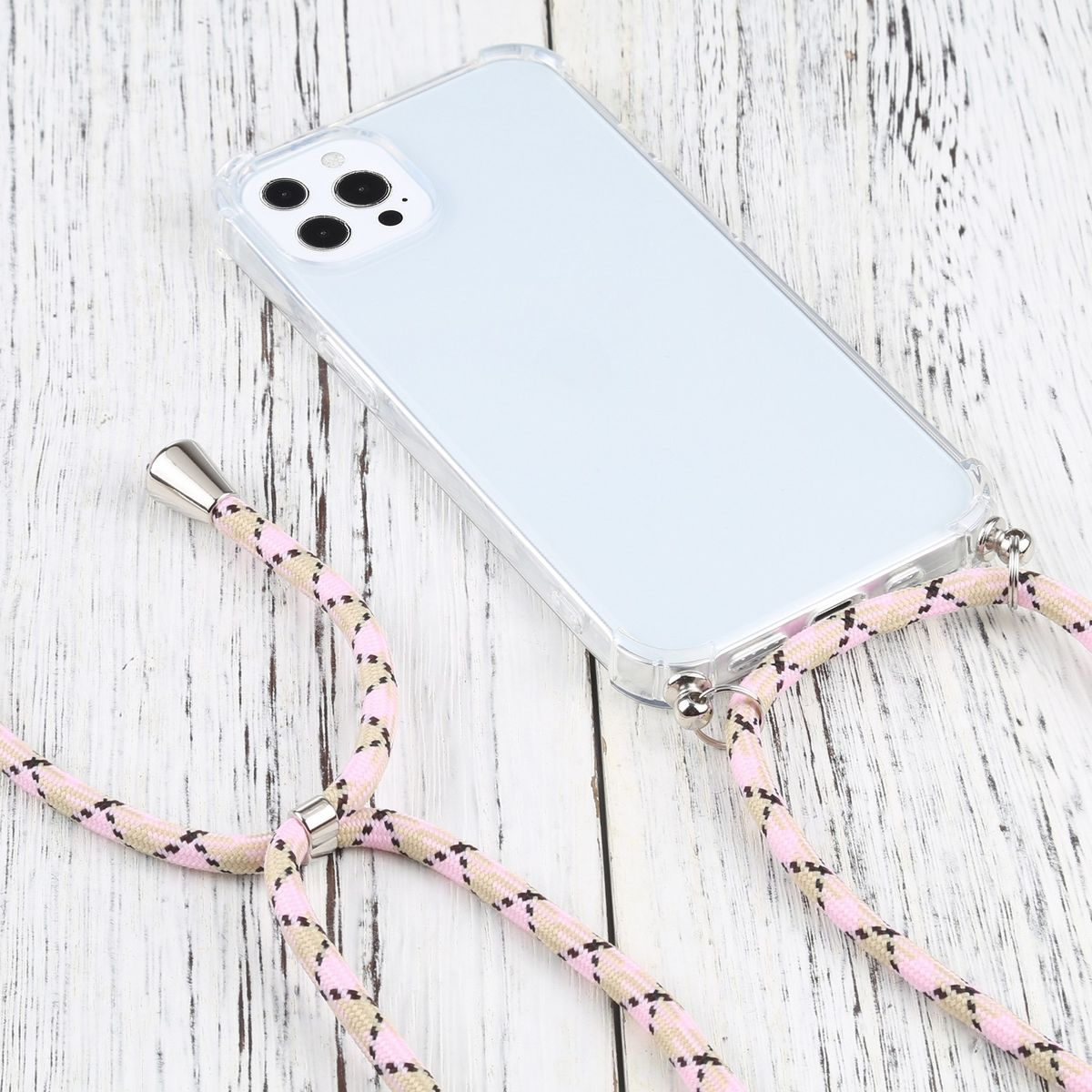 Ein Telefon mit einem rosa-beigen Band liegt auf einem weißen Holztisch. Das Band wird an der Handyhülle befestigt.
