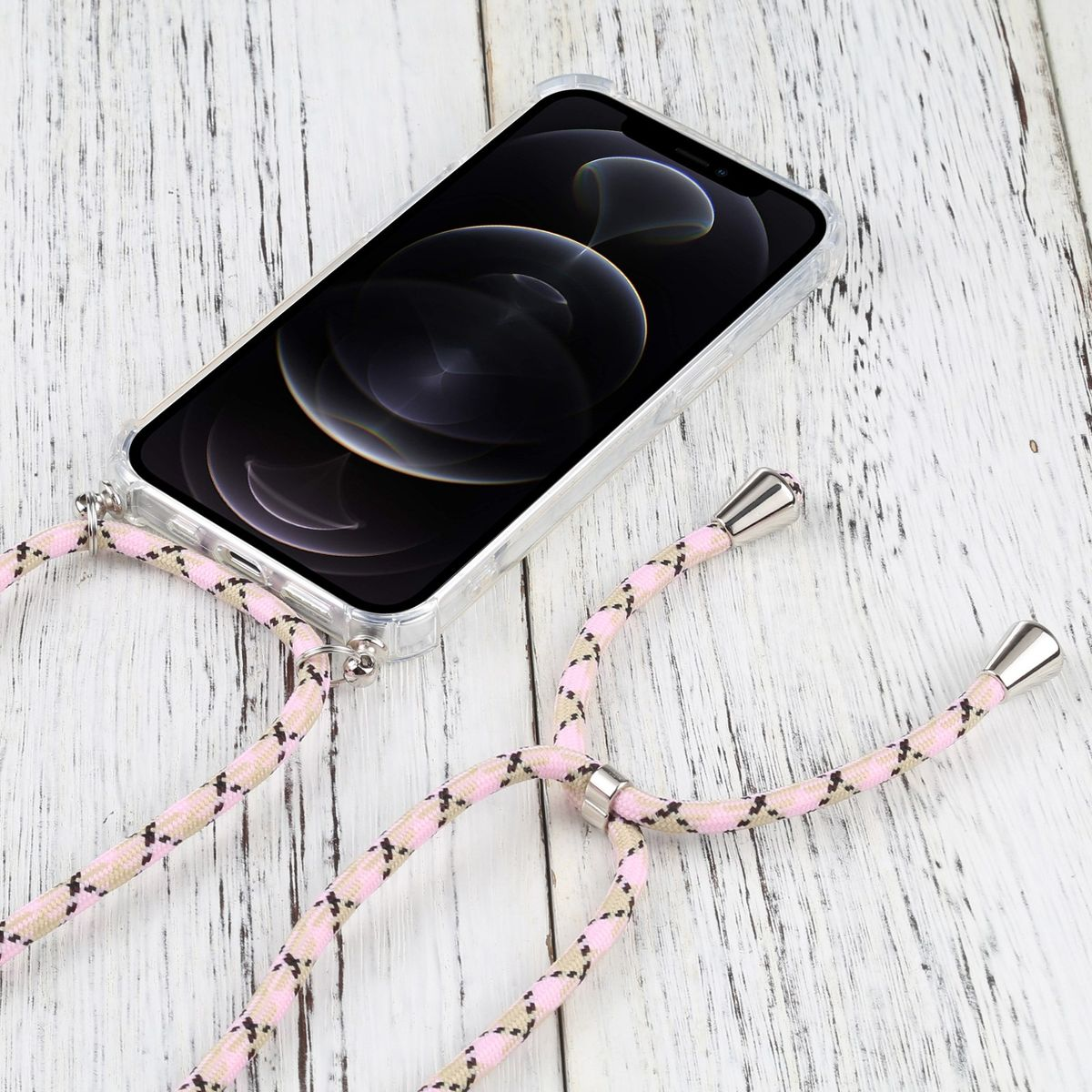 Ein Telefon mit klarer Hülle und rosa-beigem Musterriemen liegt auf Holz.