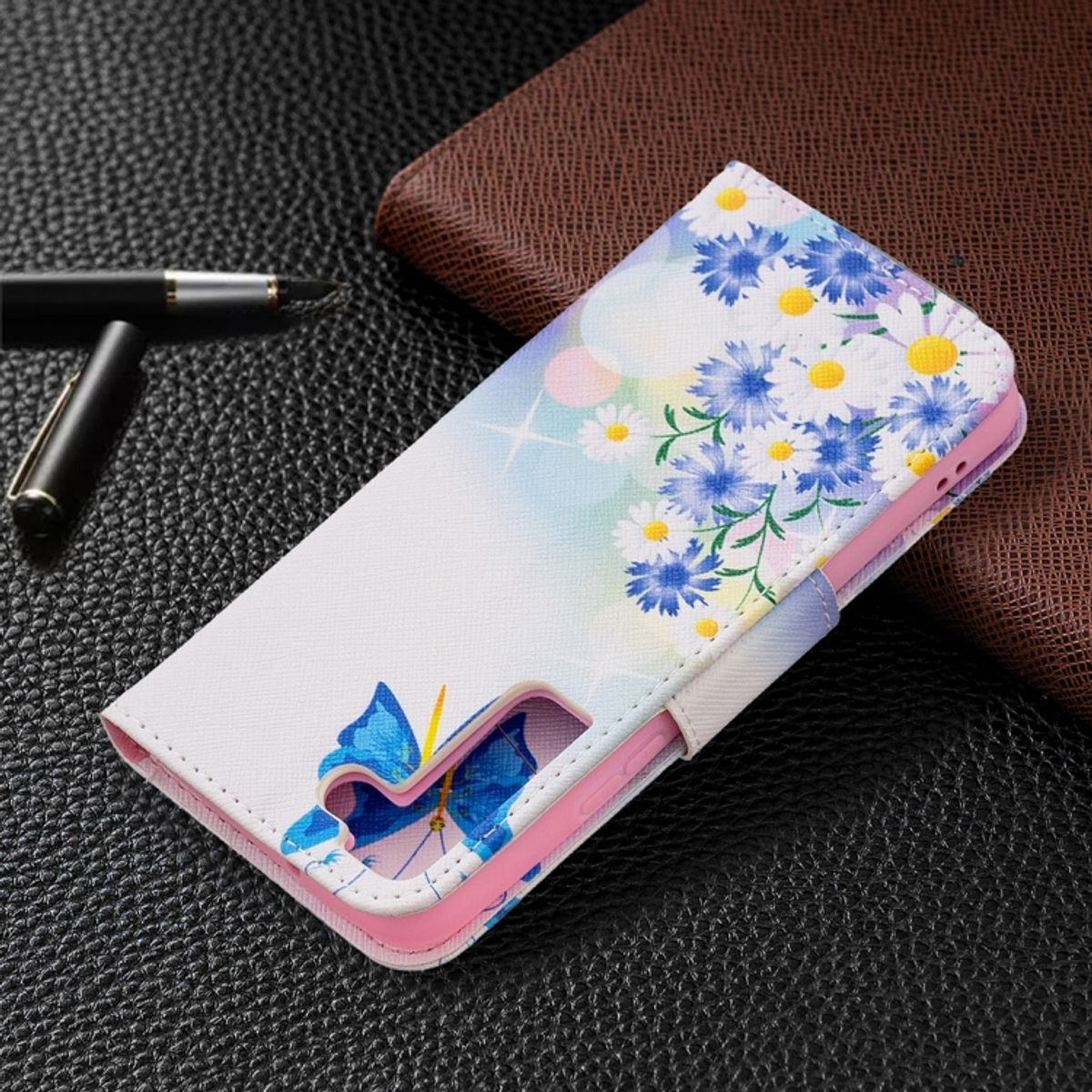 Eine Handyhülle mit floralem Design. Die Hülle ist weiß mit blauen Blumen und einem Schmetterlingsdesign.