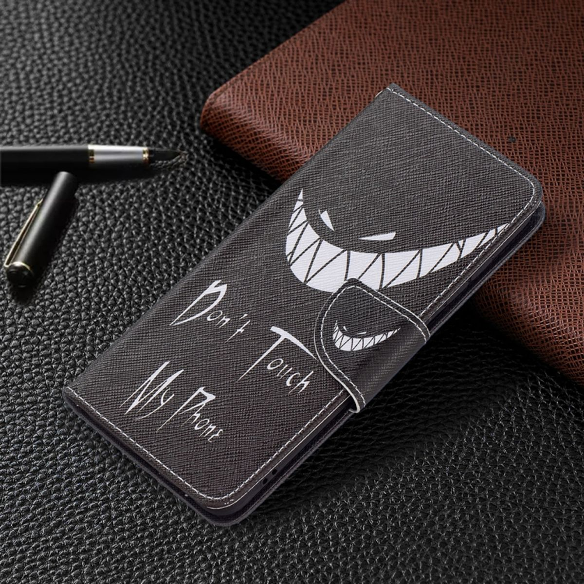 Schwarze Handyhülle mit einem lächelnden Gesichtsdesign. Der Hintergrund ist dunkles Leder.