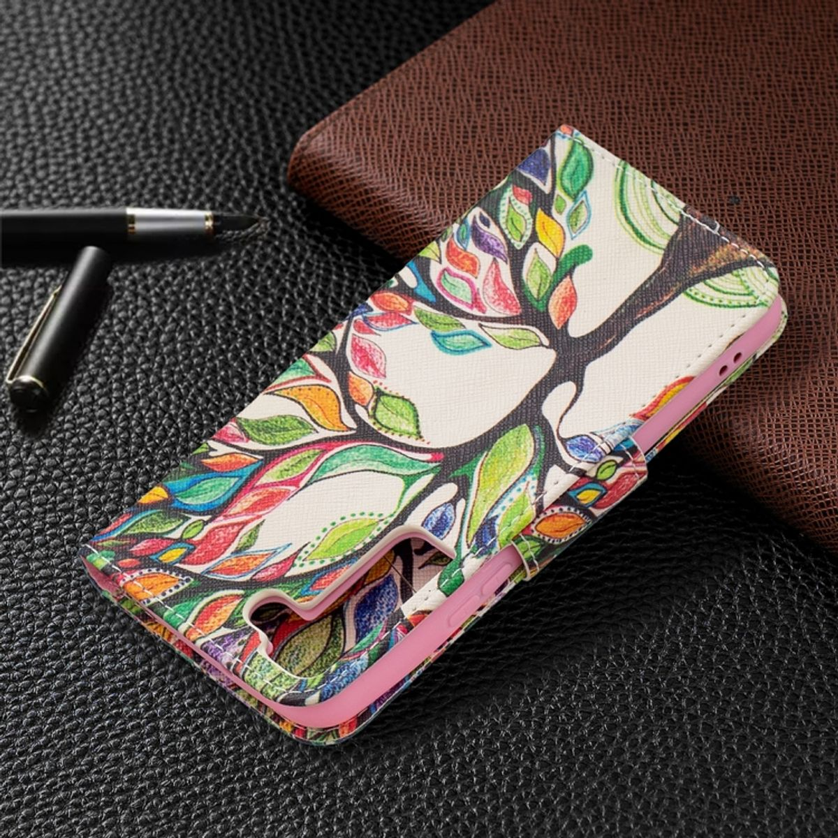 Handyhülle mit buntem Baumdesign, Stift auf Lederoberfläche.