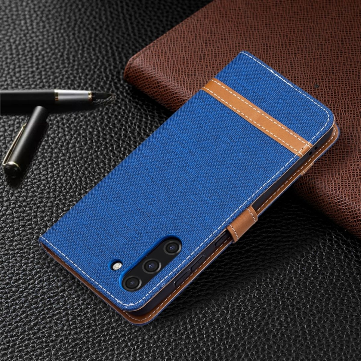 Blaue Handyhülle mit braunen Akzenten. Braunes Leder. Dunkler Hintergrund.