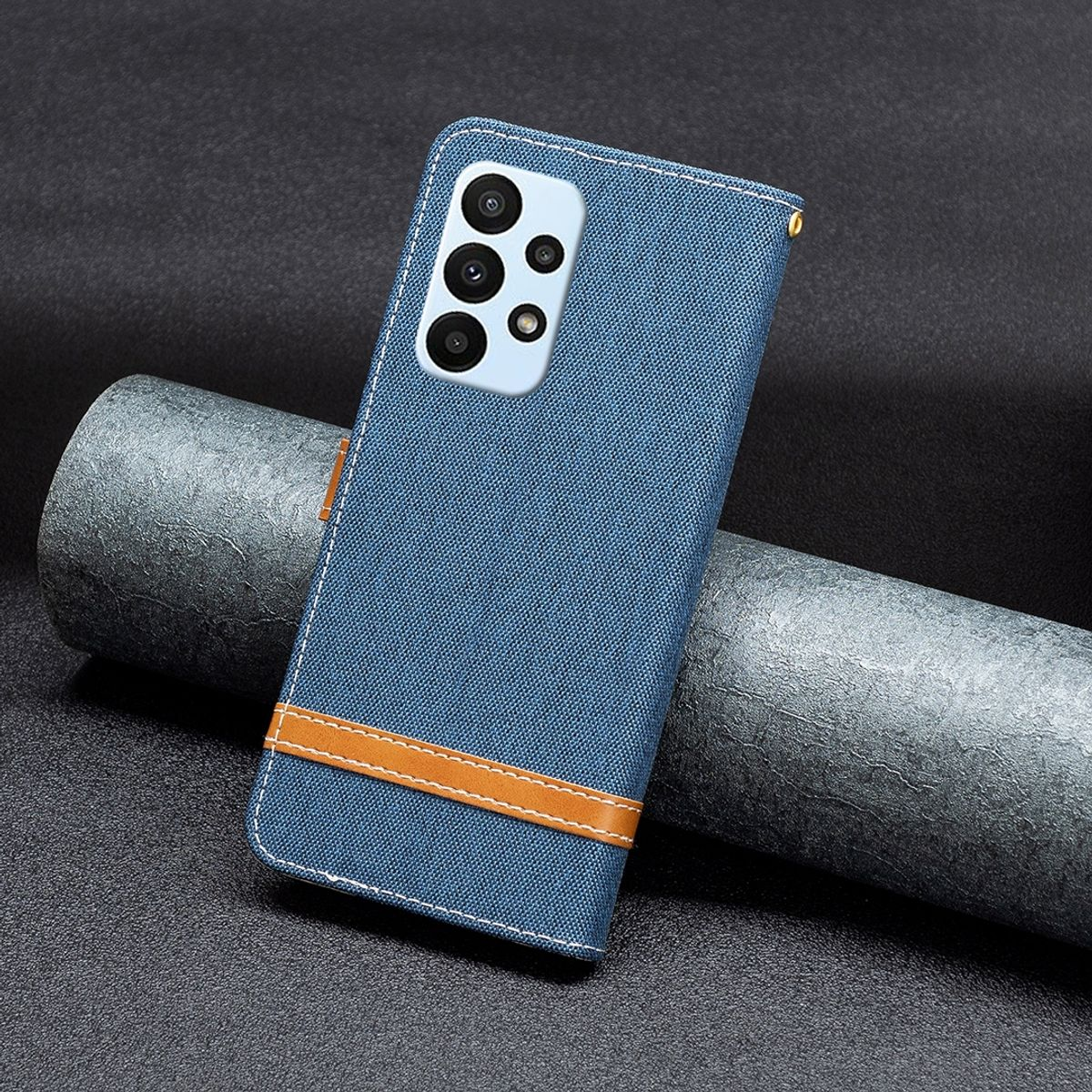 Eine blaue Jeans-Handyhülle mit braunem Lederriemen und einem Telefon. Dunkler Hintergrund.