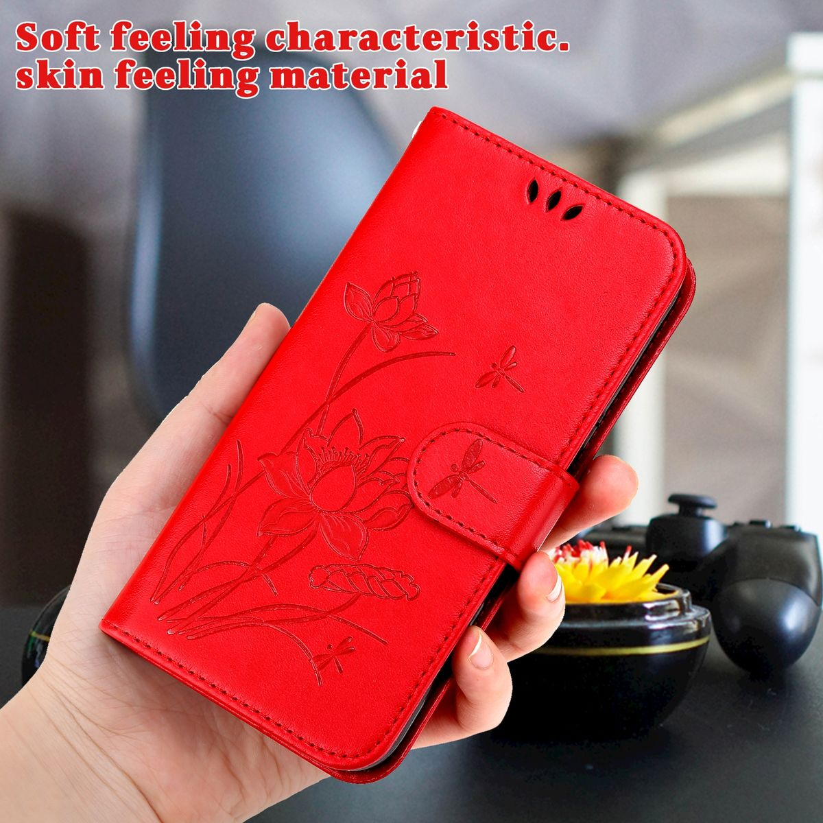 Eine rote Leder-Handyhülle mit floralem Design, gehalten in einer Hand. Die Hülle ist geschlossen.