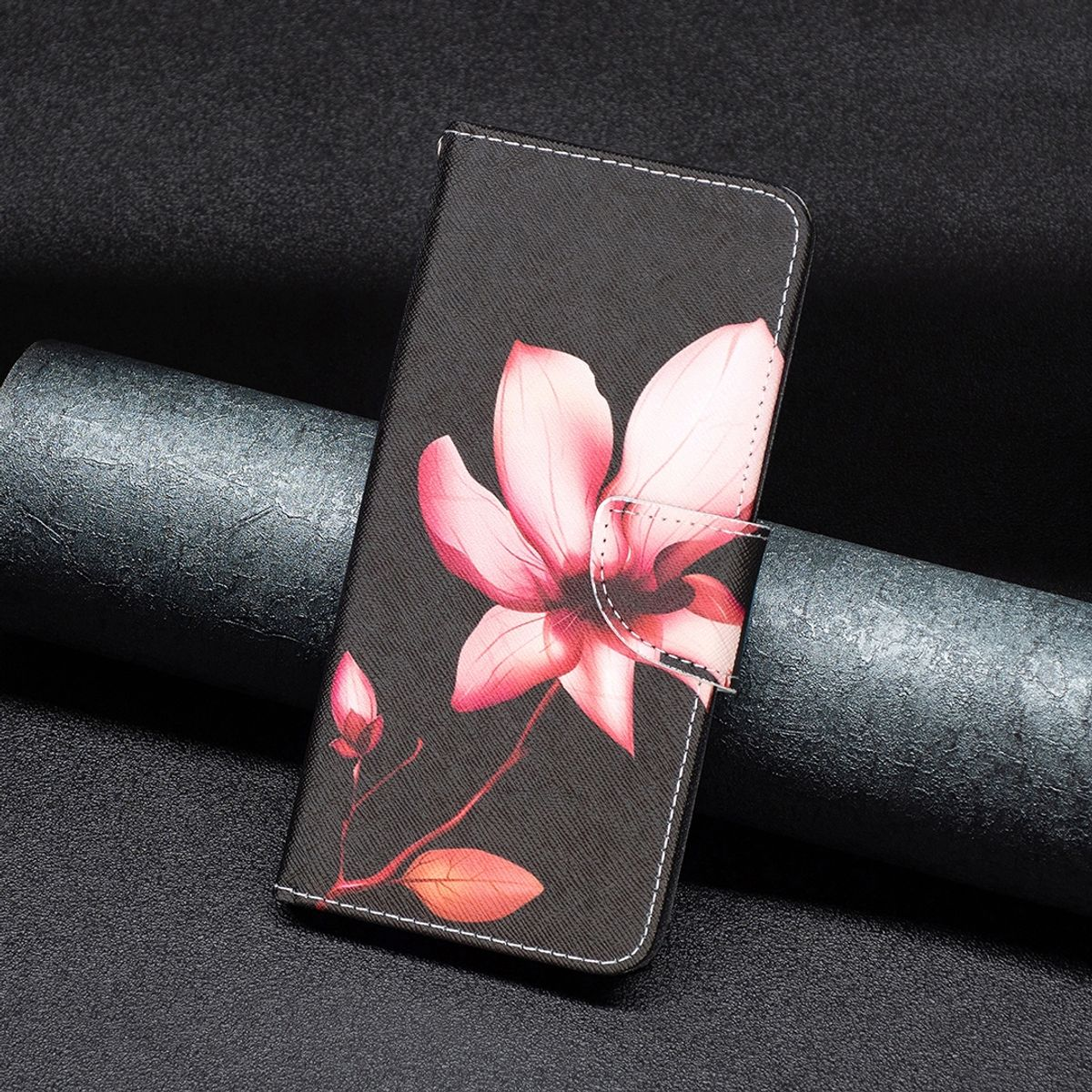 Handyhülle mit pinkfarbenem Blumendesign auf dunklem Hintergrund. Die Hülle ist geschlossen.