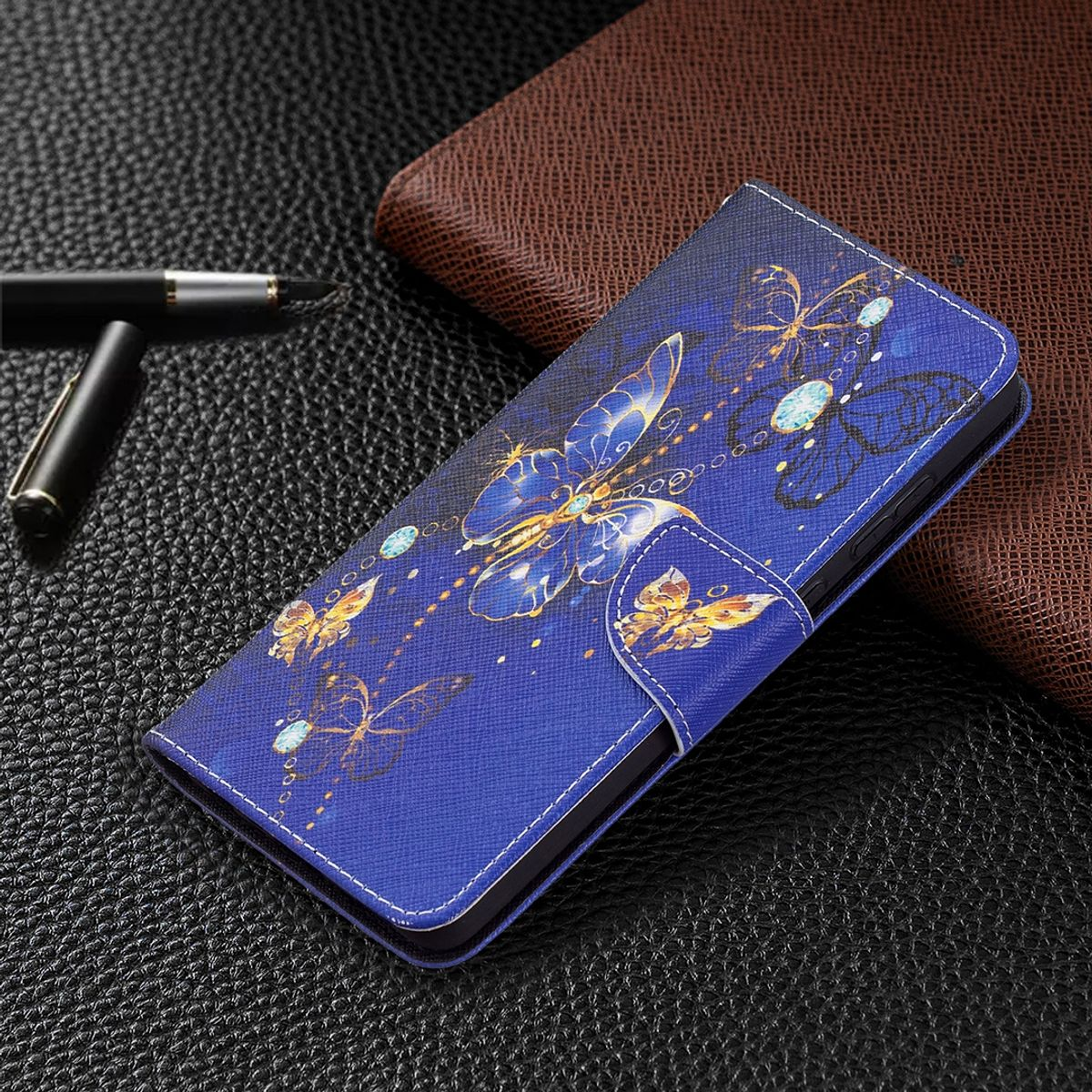 Offene Handyhülle mit Schmetterlingsdesign. Blaue Hülle, schwarze Oberfläche und ein Stift.