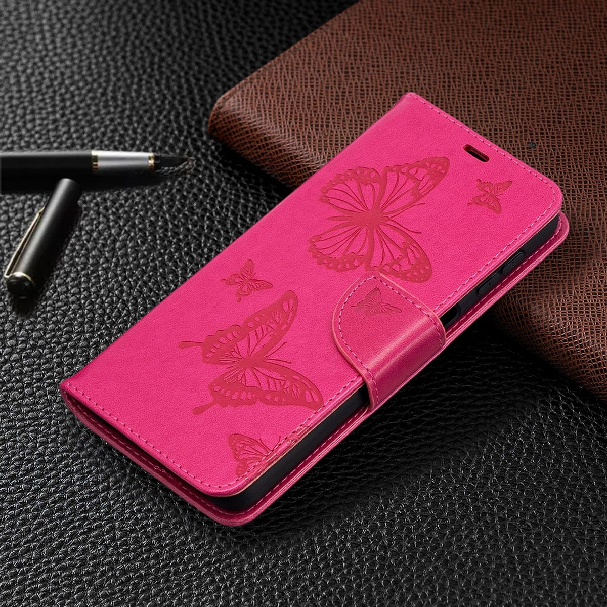Rosa Handyhülle mit Schmetterlingsdesign, geschlossen. Auf dunkler Oberfläche.