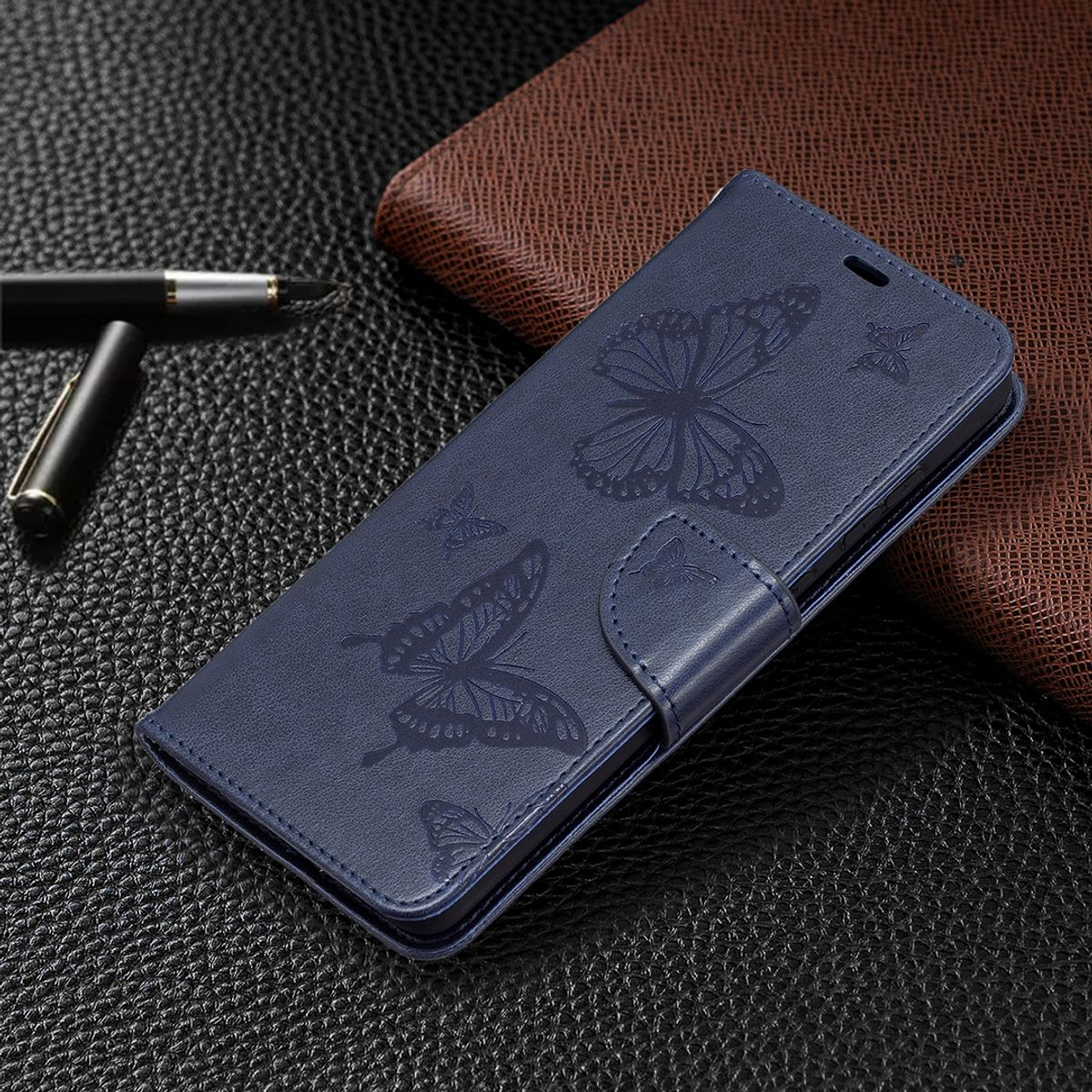 Blaue Handyhülle mit Schmetterlingsdesign, auf einer schwarzen und braunen Lederoberfläche.