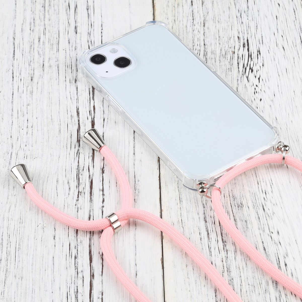 Transparente Handyhülle mit rosa Kordelhalskette. Telefon liegt auf weißer Holzoberfläche.