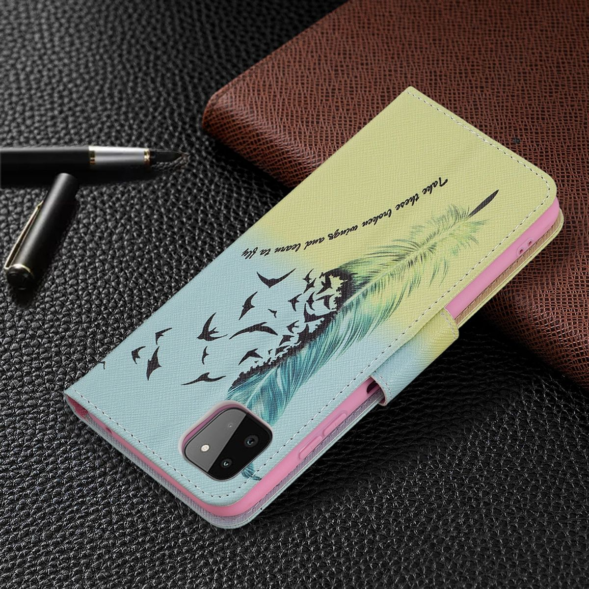 Handyhülle mit Feder- und Vogeldesign. Stift und Geldbörse im Hintergrund.