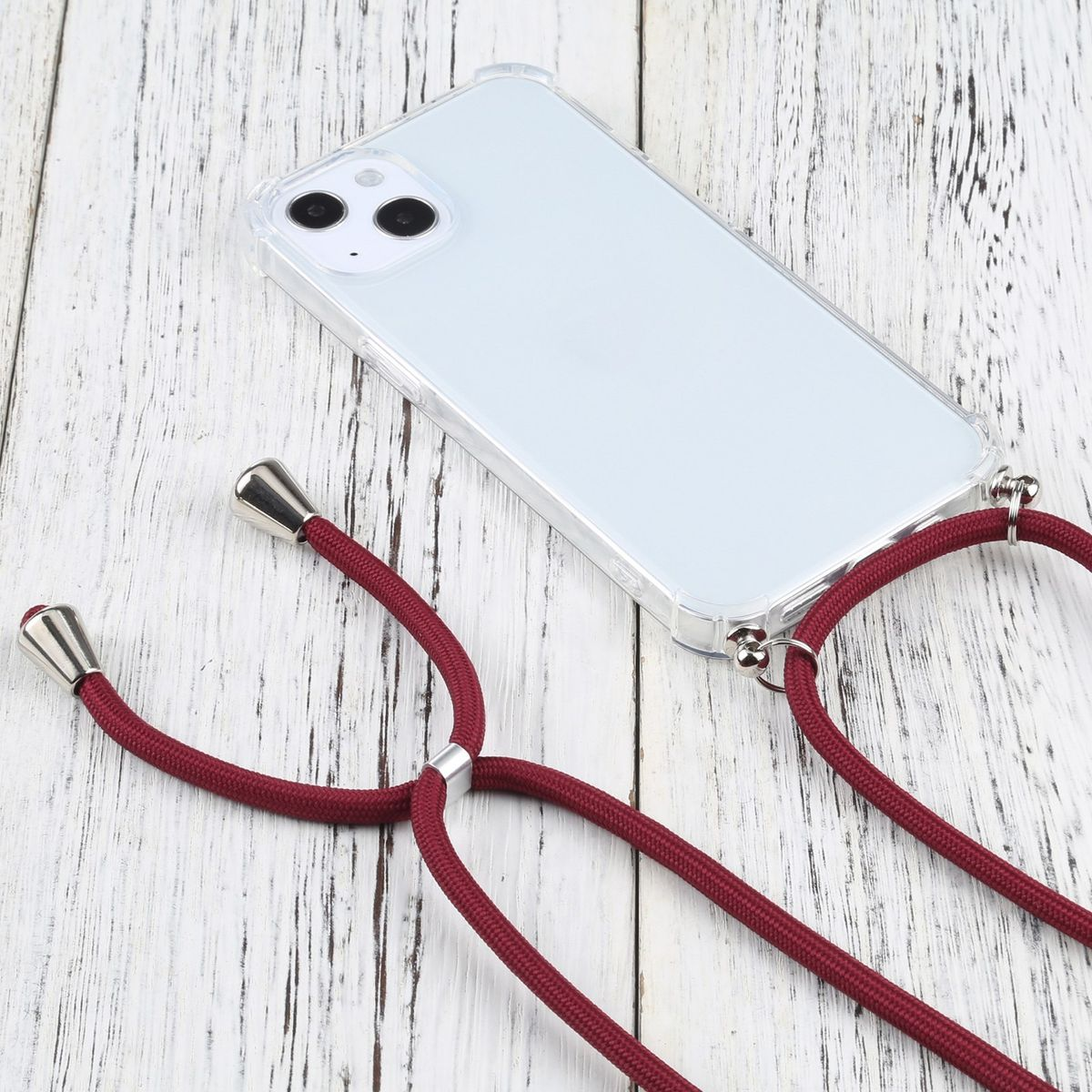 Transparente Handyhülle mit rotem Schlüsselband. Das Telefon ist weiß. Das Schlüsselband hängt über einer Holzoberfläche.