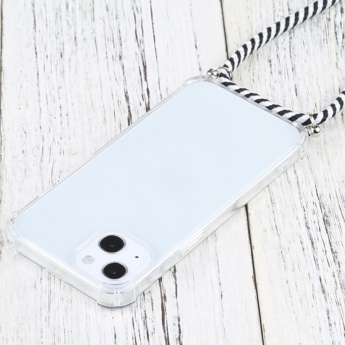 Transparente Handyhülle mit Trageriemen. Das Telefon liegt auf Holz, der Riemen ist schwarz-weiß.