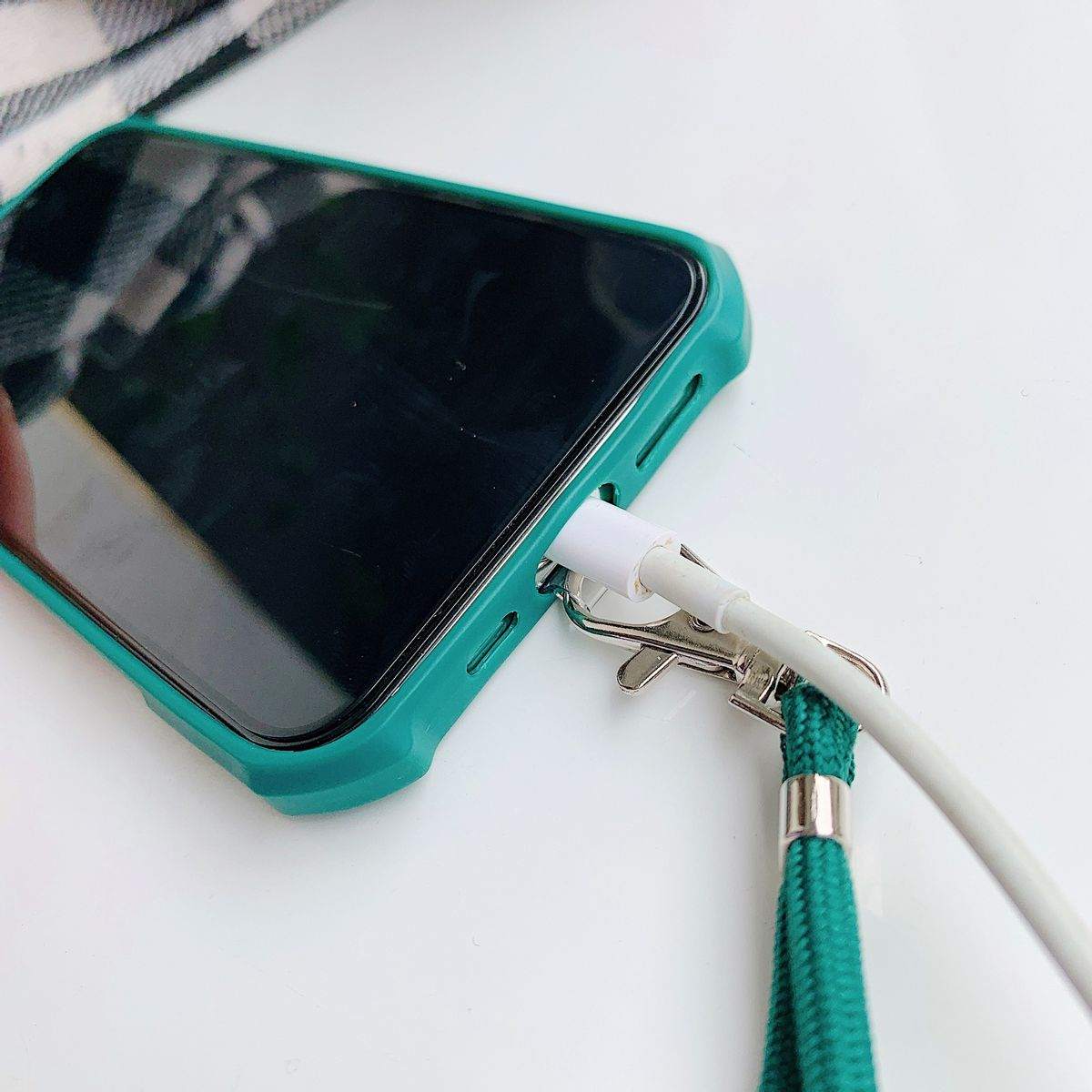 Telefon mit grünem Gehäuse, lädt mit weißem Kabel. Weißer Hintergrund.