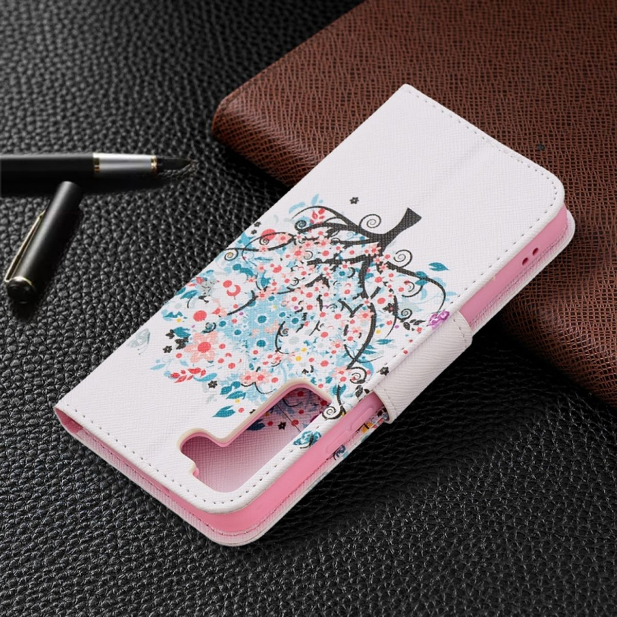 Weiße Handyhülle mit floralem Design und rosa Innenraum. Brauner Hintergrund.