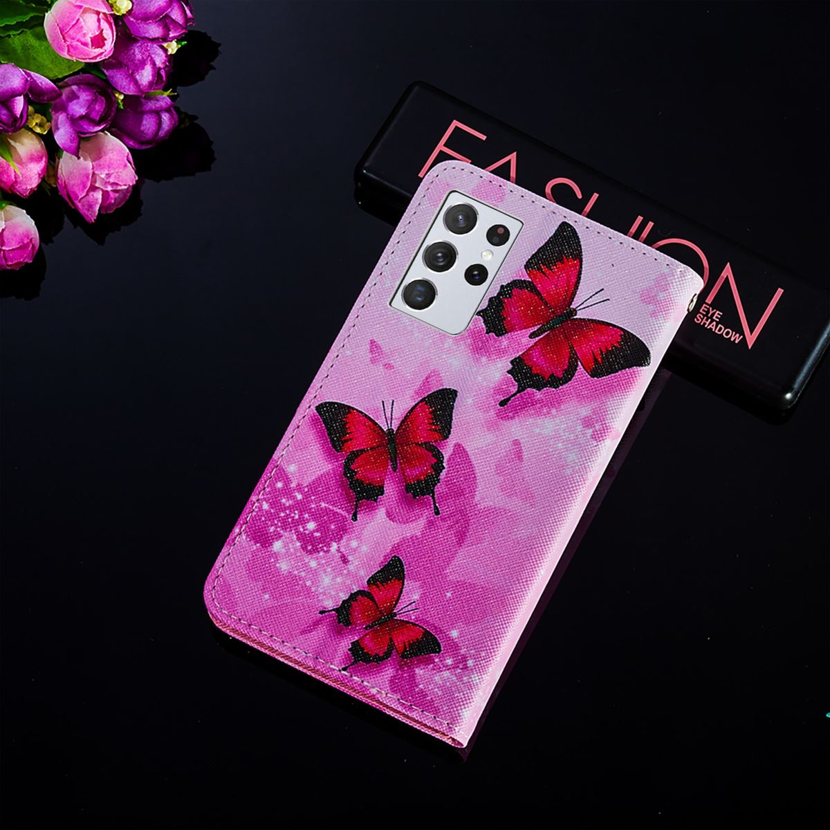 Rosa Handyhülle mit Schmetterlingen auf der Rückseite. Eine schwarze Hülle für das Telefon ist innen sichtbar.
