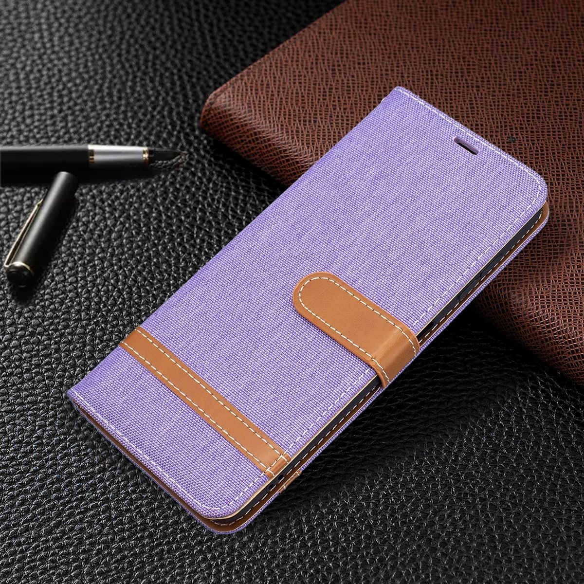 Eine lilafarbene Handyhülle mit braunem Riemen. Die Hülle ist geöffnet und zeigt ein Telefon im Inneren.