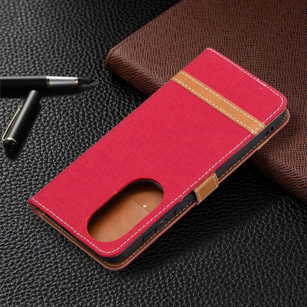 Rote Handyhülle mit zweifarbigem Design, geschlossen. Auf dunkler Oberfläche.