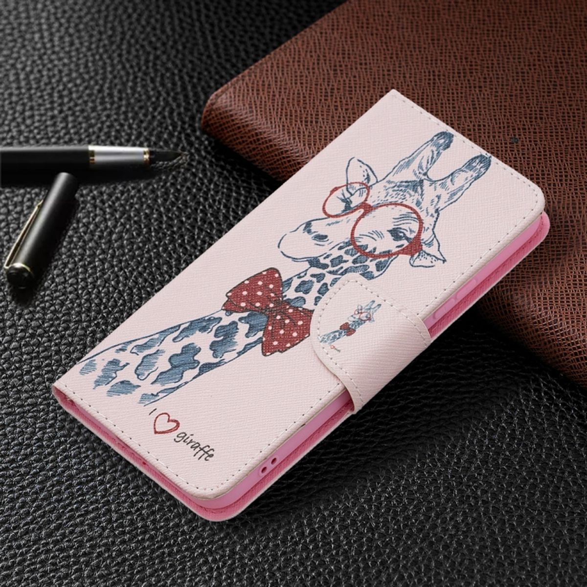 Rosa Handyhülle mit Giraffen-Design und Brille auf dunkler Oberfläche.
