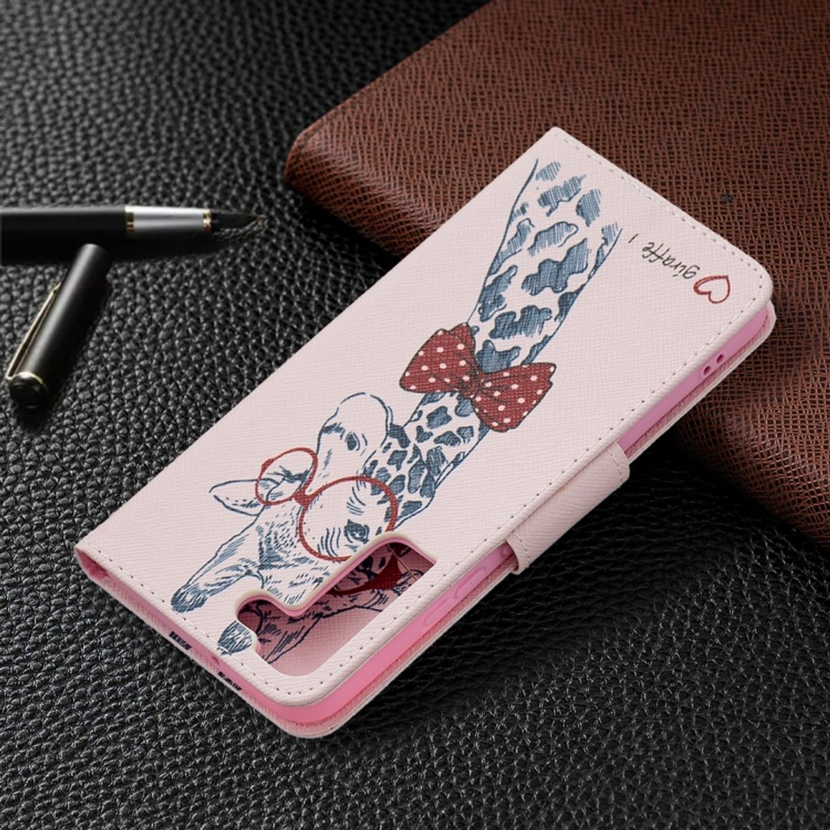 Rosa Giraffen-Handyhülle mit Giraffen-Design. Stift und Geldbörse im Hintergrund.
