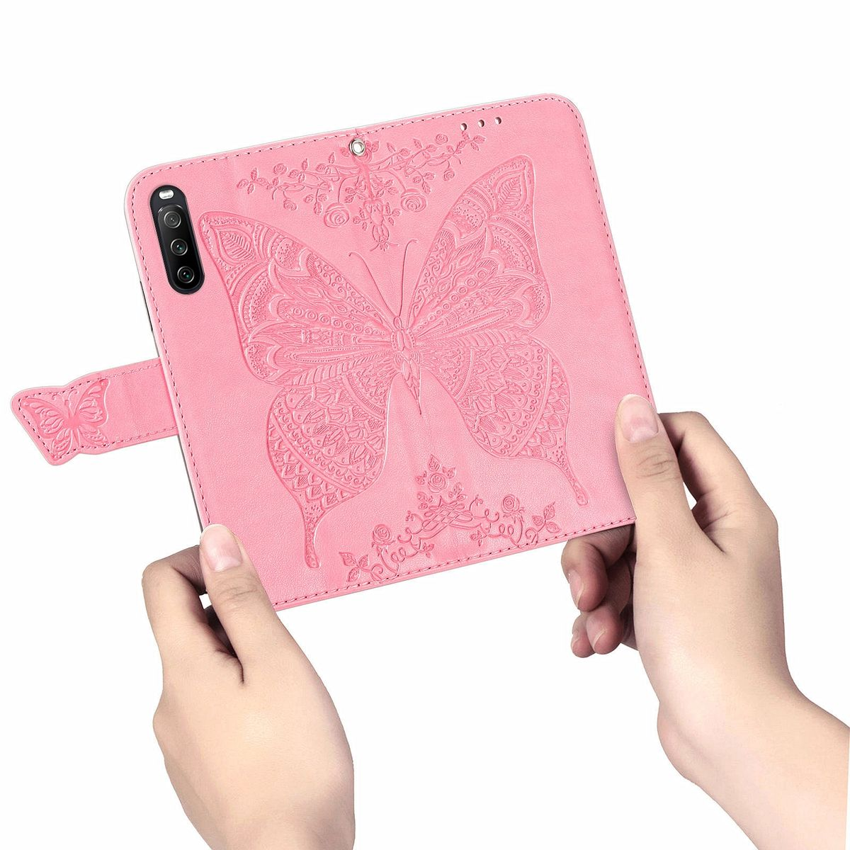 Rosa Handyhülle mit Schmetterlingsdesign, gehalten von zwei Händen. Der Schmetterling ist geprägt und detailliert. Weißer Hintergrund.