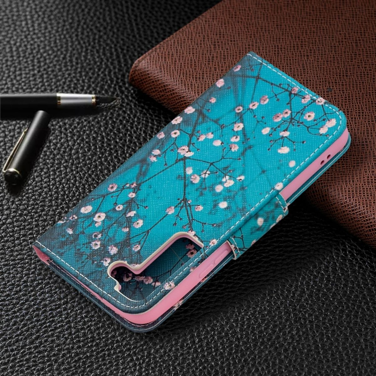 Blaue Handyhülle mit floralem Design. Die Hülle ist offen. Ein Stift und eine Geldbörse sind im Hintergrund.