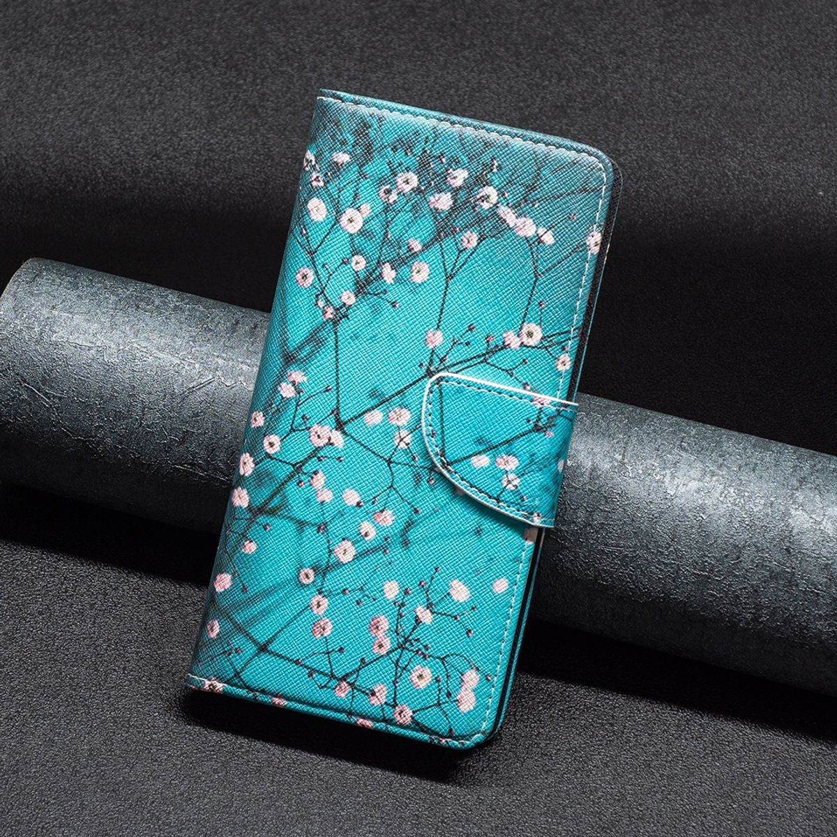 Türkisfarbene Handyhülle mit Blumendesign und einem Telefon darin. Die Hülle ist geschlossen.