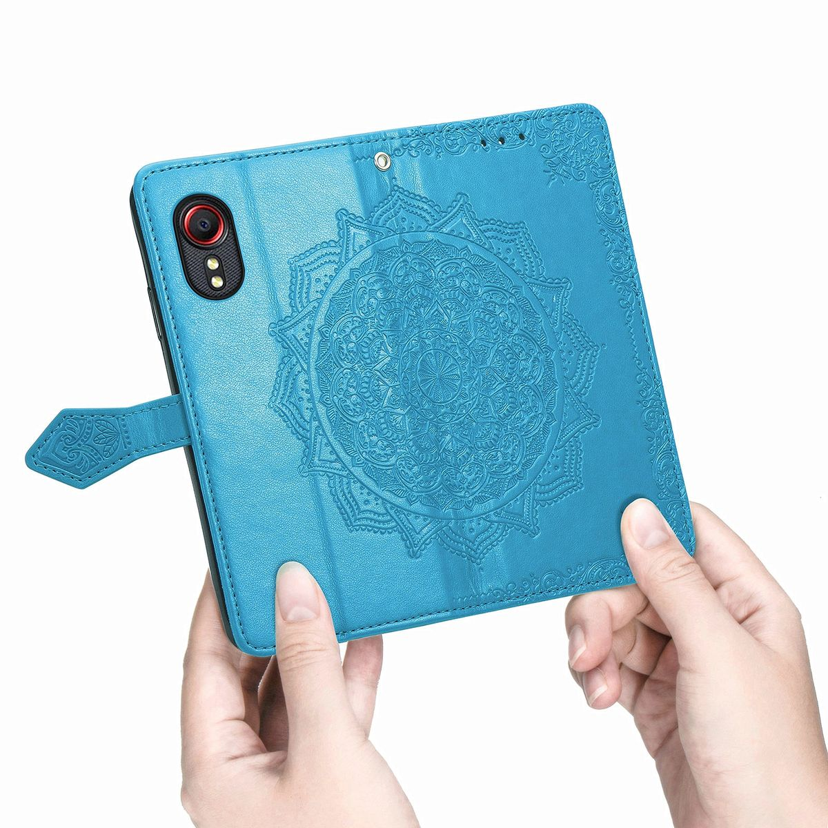 Hände halten eine türkisfarbene Handyhülle mit Mandalamuster auf einer blauen Lederoberfläche.