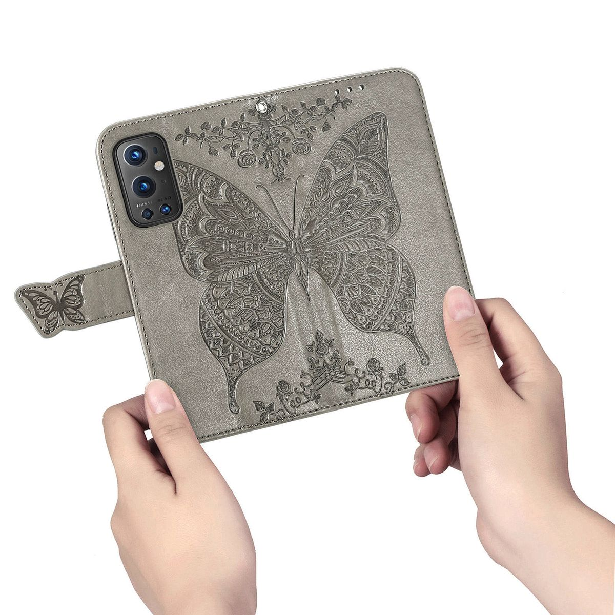 Graue Handyhülle mit Schmetterlingsdesign. Hände halten es. Der Hintergrund ist weiß.