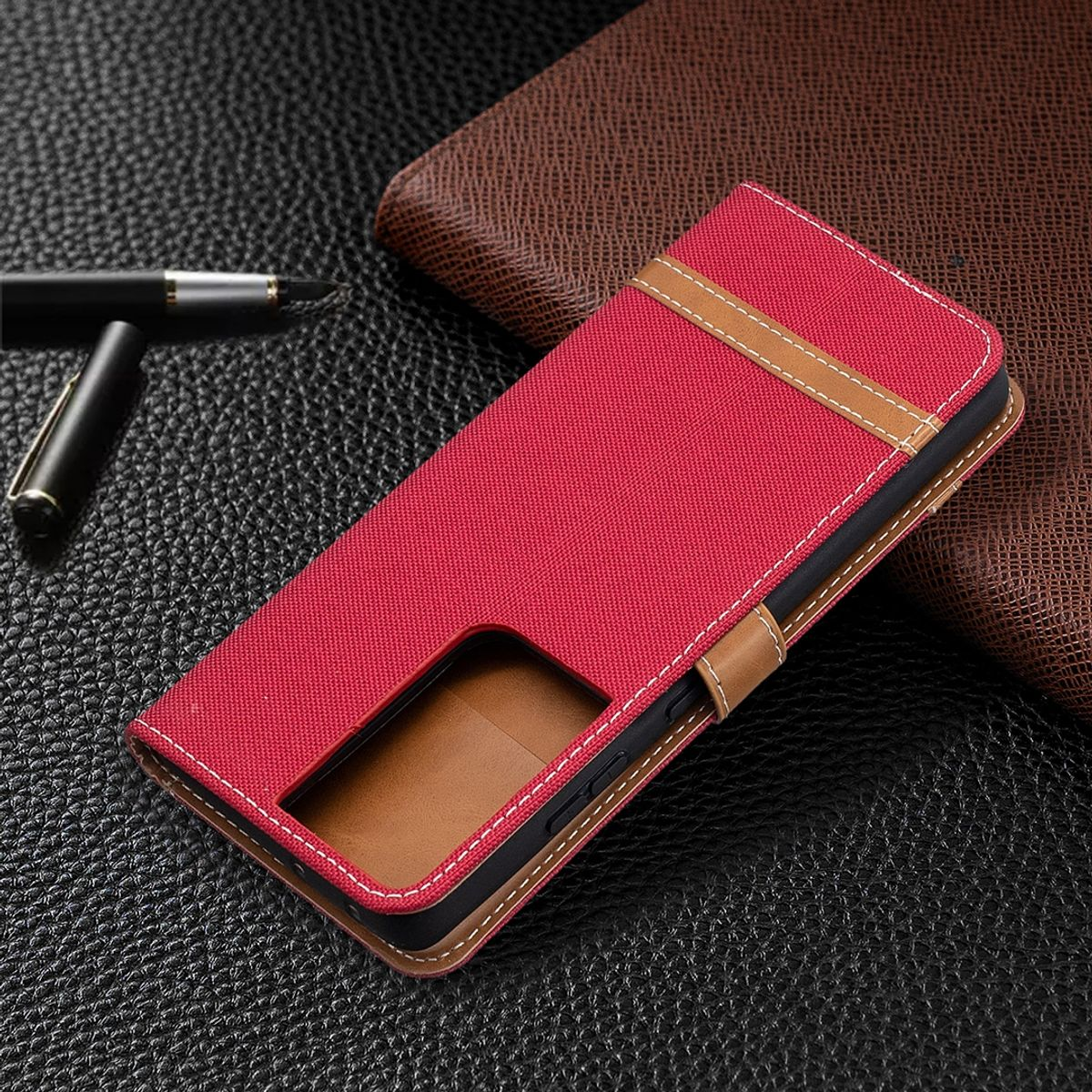 Rote Handyhülle mit braunen Akzenten. Stift und ein braunes Notizbuch sind sichtbar.