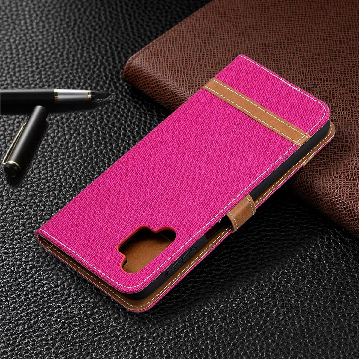 Pinke Handyhülle, geschlossen, mit Stift und Lederhintergrund. Braune und weiße Details auf dem Cover.