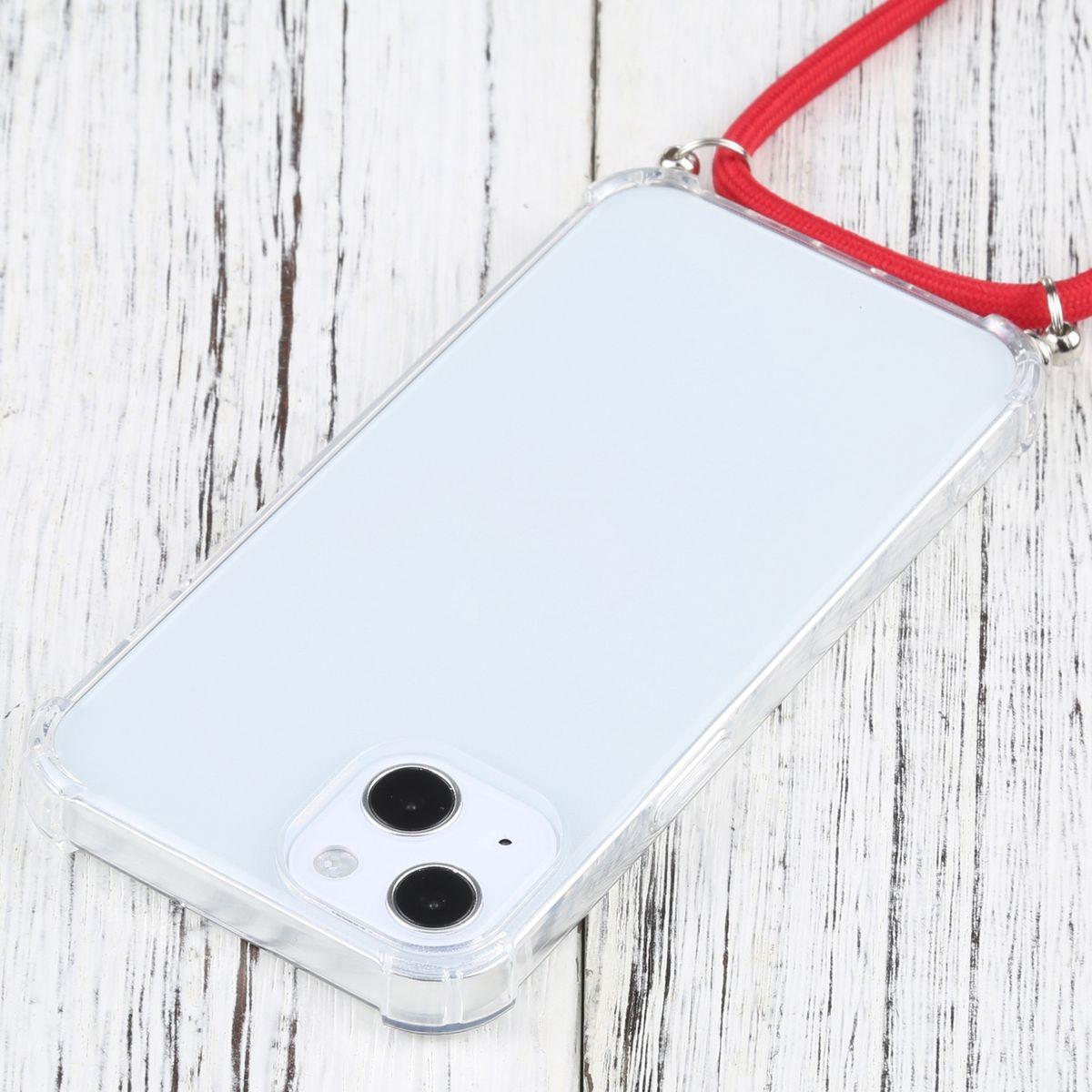 Transparente Handyhülle mit Telefon, rotem Umhängeband. Das Telefon liegt auf Holz.
