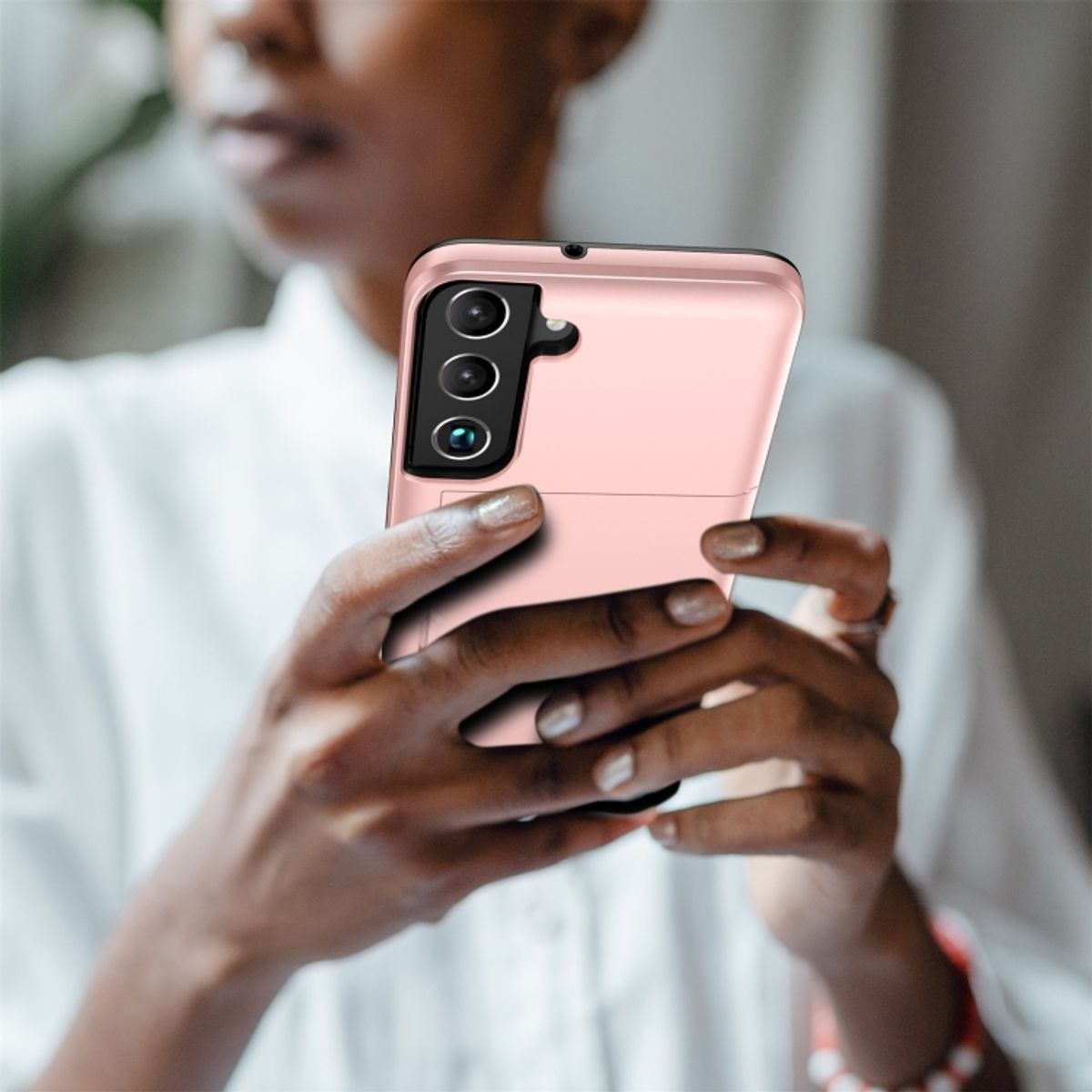 Eine Frau hält eine rosa Handyhülle. Das Telefon hat drei Kameralinsen.