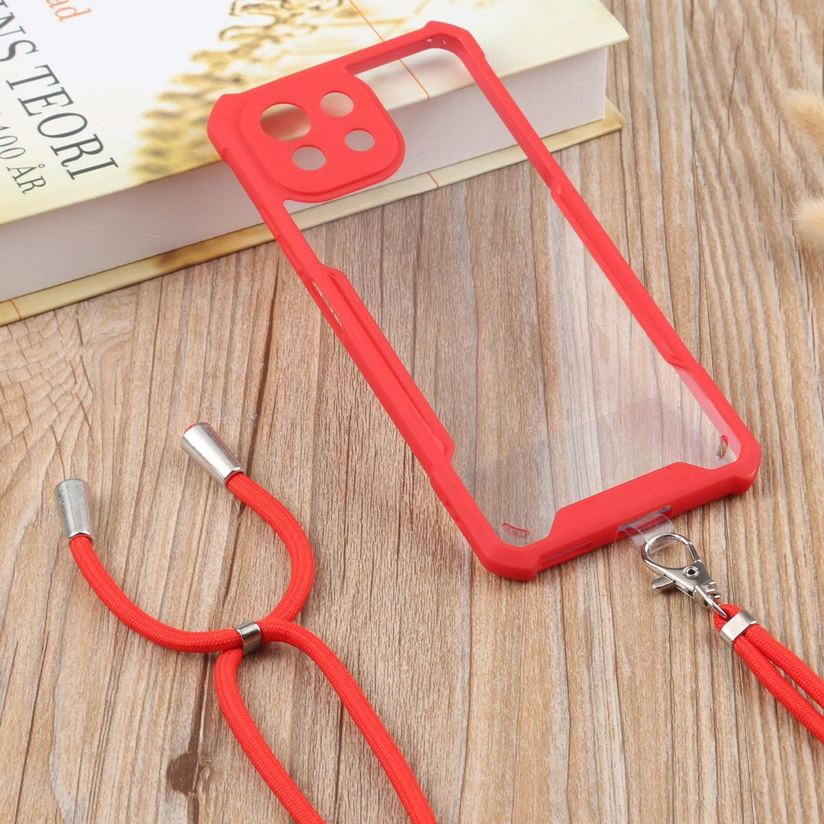 Eine rote Handyhülle mit Lanyard, liegend auf einem Holztisch mit Buch.