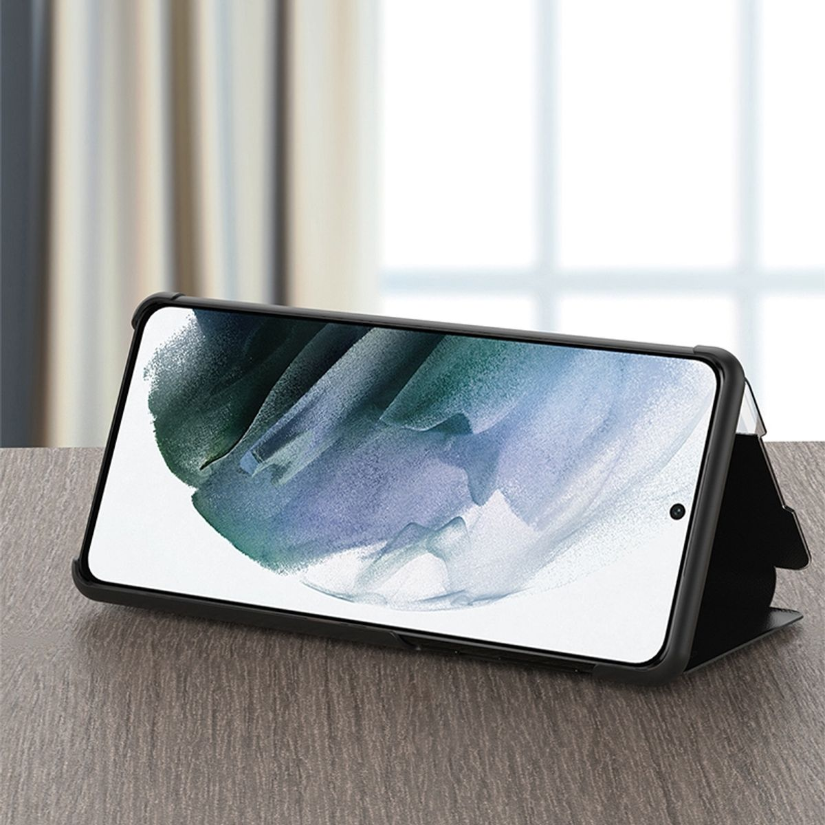 Telefon in schwarzer Hülle, steht auf Holztisch. Der Bildschirm ist an.