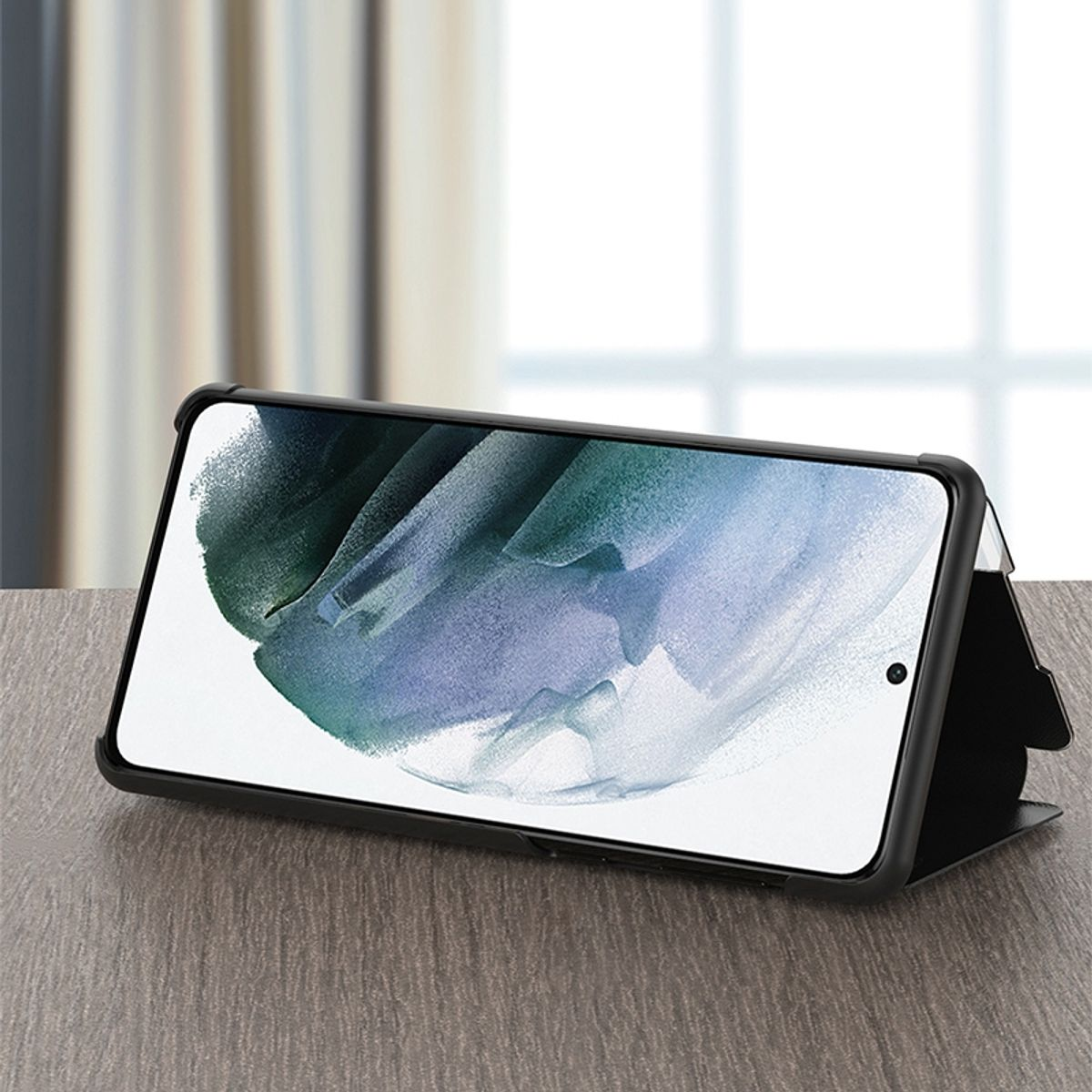Ein Smartphone in einer schwarzen Hülle, auf einem Holztisch aufgestellt, und ein verschwommener Hintergrund.
