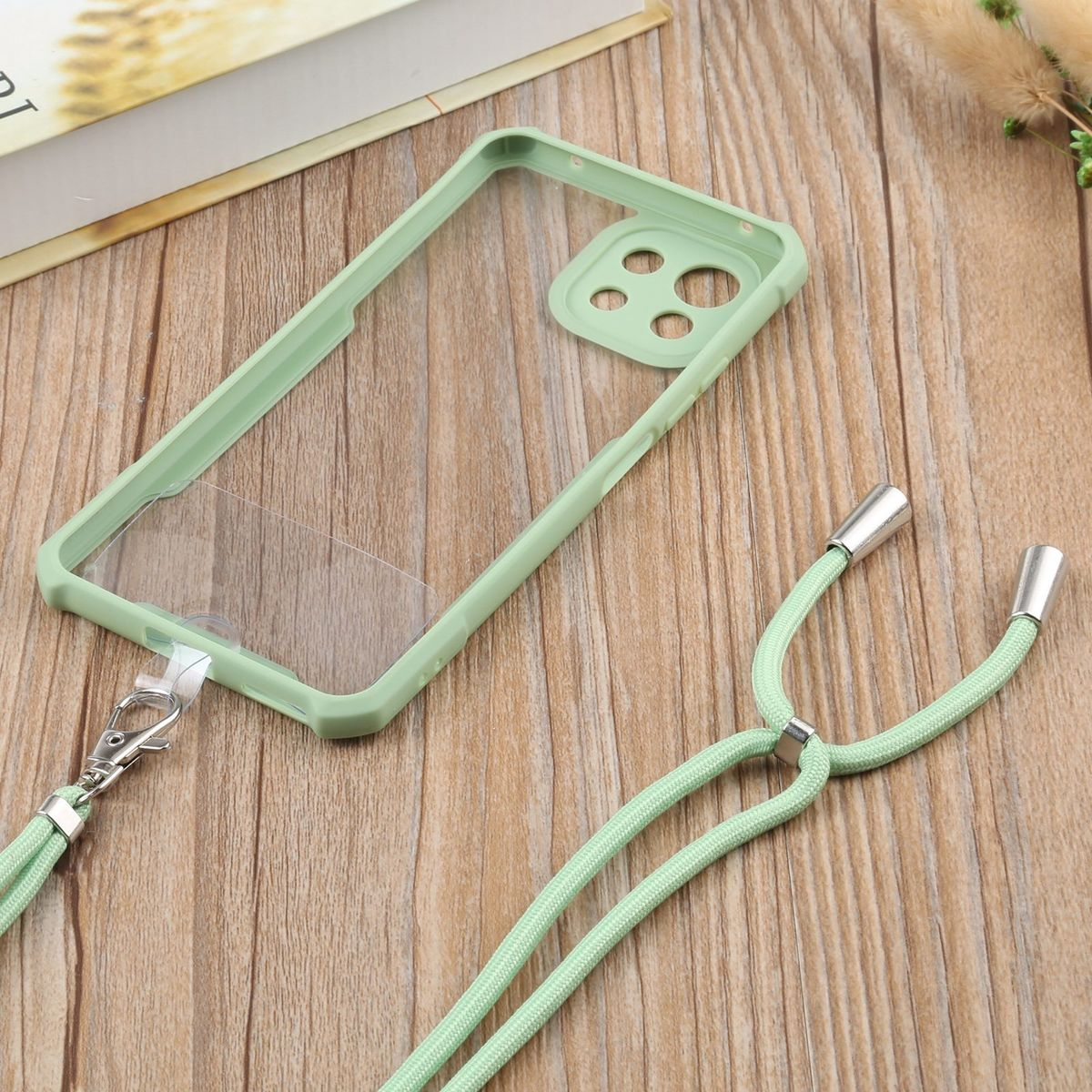 Transparente Handyhülle mit grünem Rahmen und Lanyard. Holzoberfläche. Hülle auf der Oberfläche.