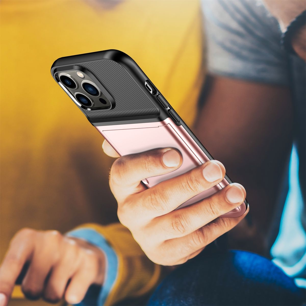 Person hält ein Telefon in einer rosa-schwarzen Hülle. Gelber Hintergrund.