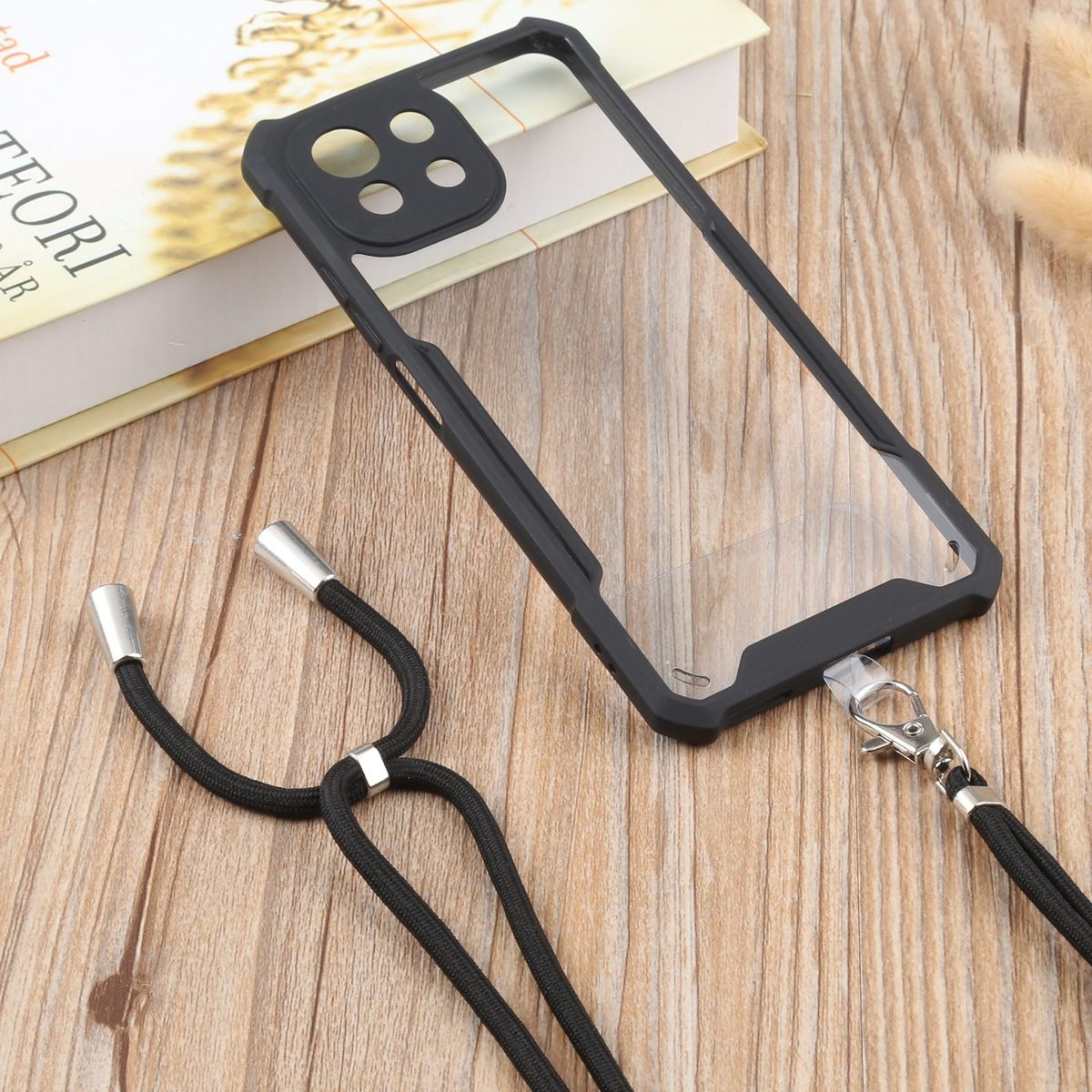 Schwarze Handyhülle mit Umhängeband. Die Hülle ist an einem schwarzen Kabel befestigt.