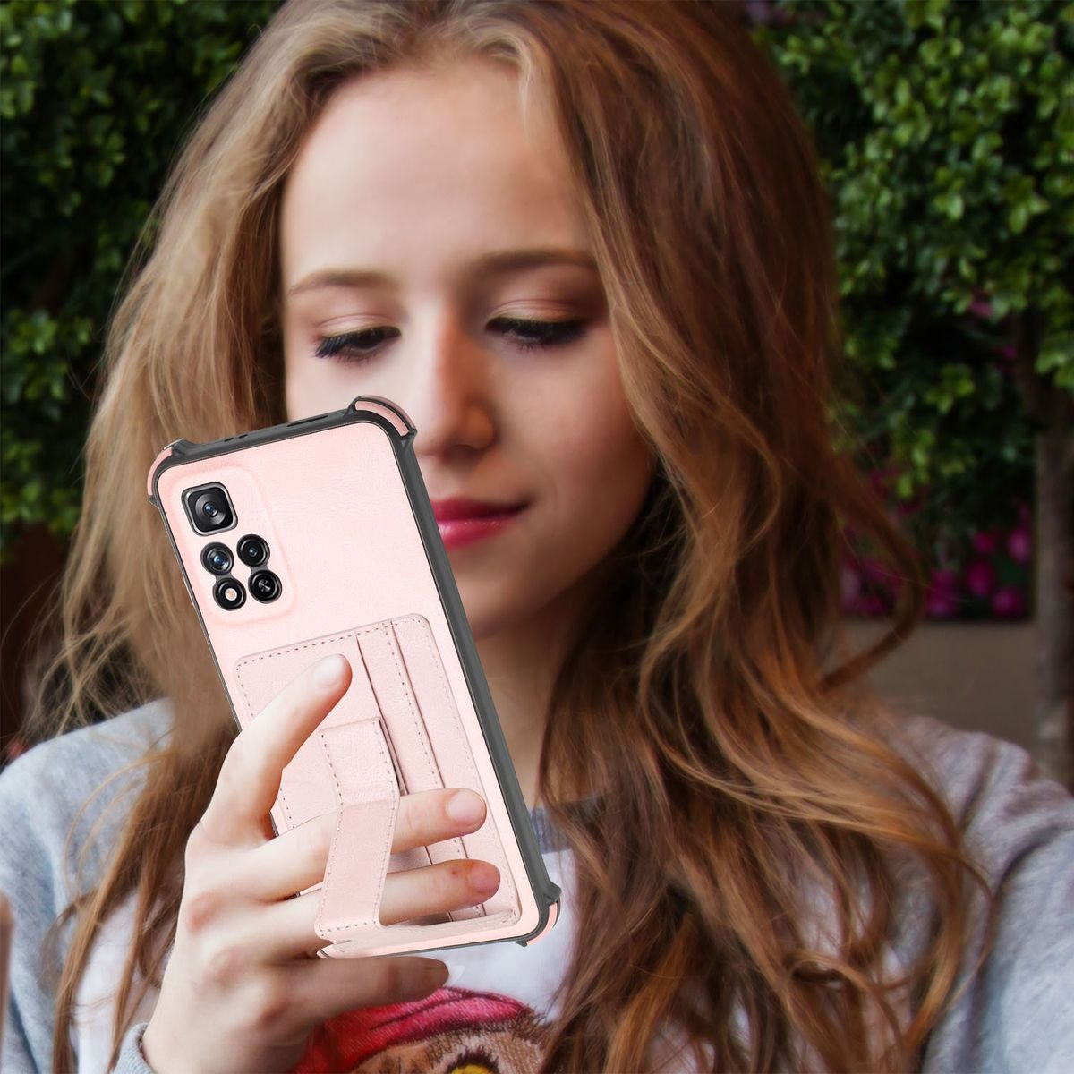 Frau hält ein rosa Telefon mit Hülle und Ständer, lächelt.