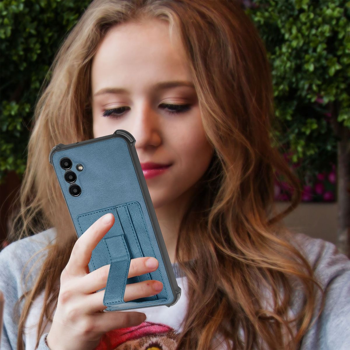 Eine Frau hält ein blaues Telefon mit einer blauen Handyhülle. Das Telefon hat einen Ständer.