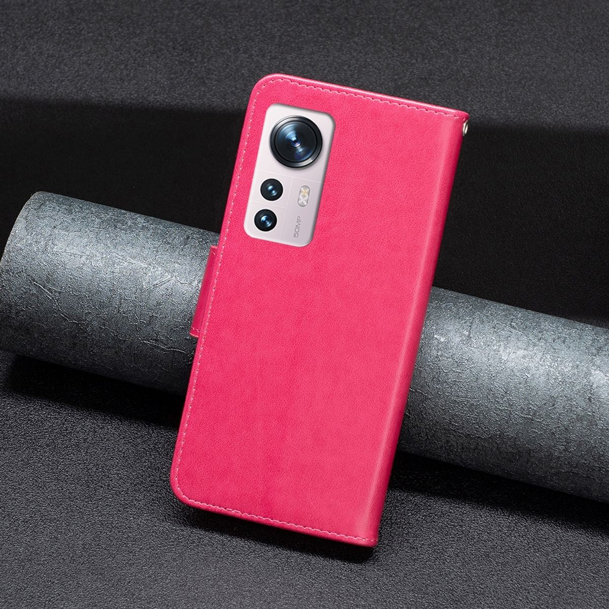 Rosa Handyhülle mit Telefon. Die Hülle ist angewinkelt. Dunkler Hintergrund. Kamera sichtbar.