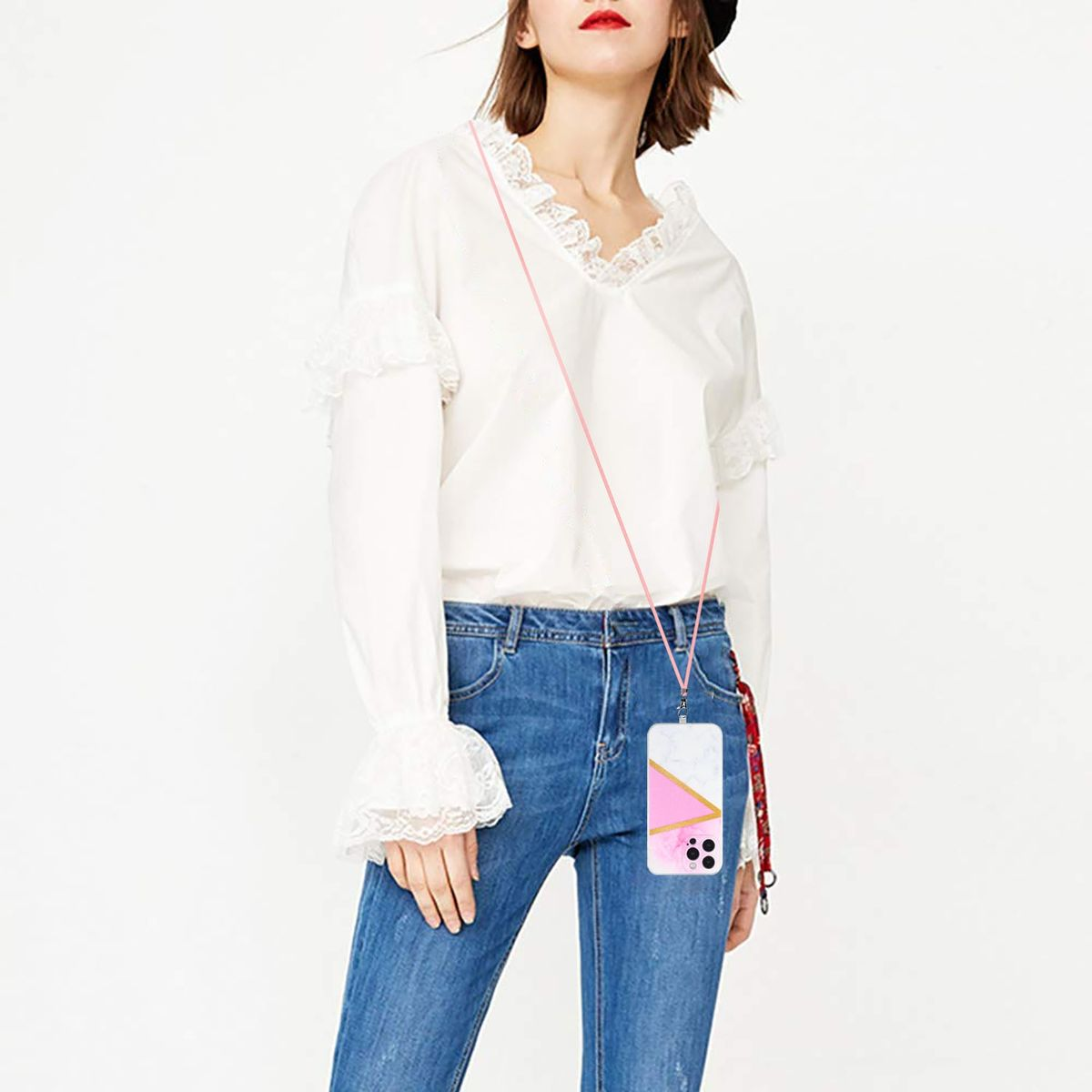 Frau mit weißem Hemd und Jeans, die ein Telefon mit pinkfarbener gemusterter Hülle hält.